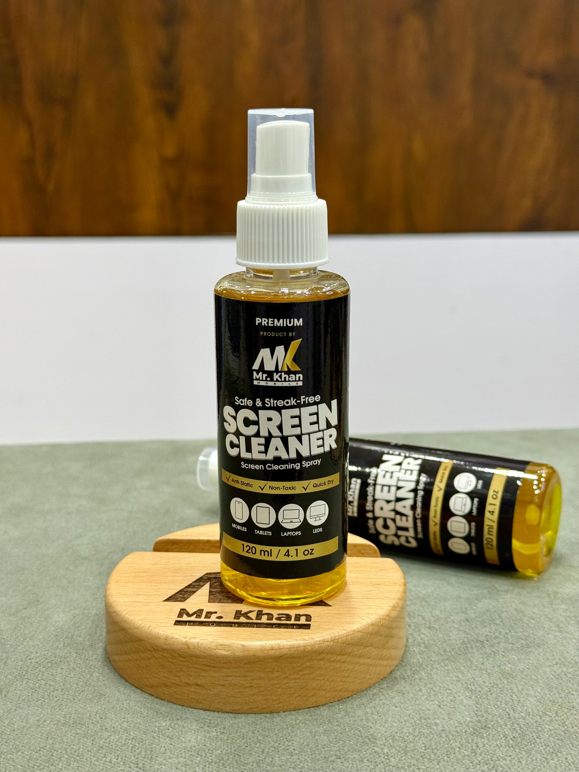 Bottle of Mr. Khan screen cleaner on a wooden stand with a blurred background