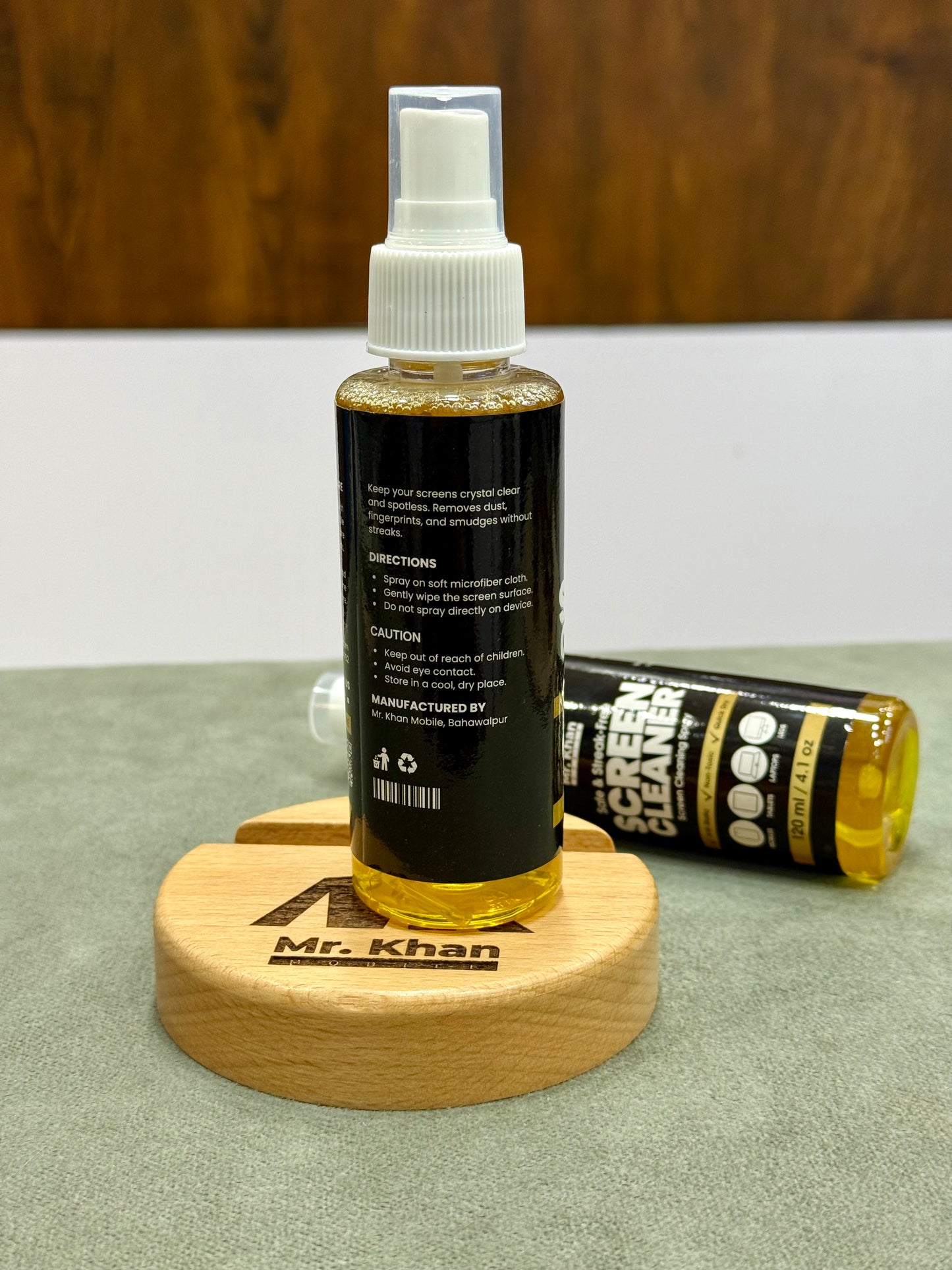 Bottle of screen cleaner with a wooden coaster and tube on a surface
