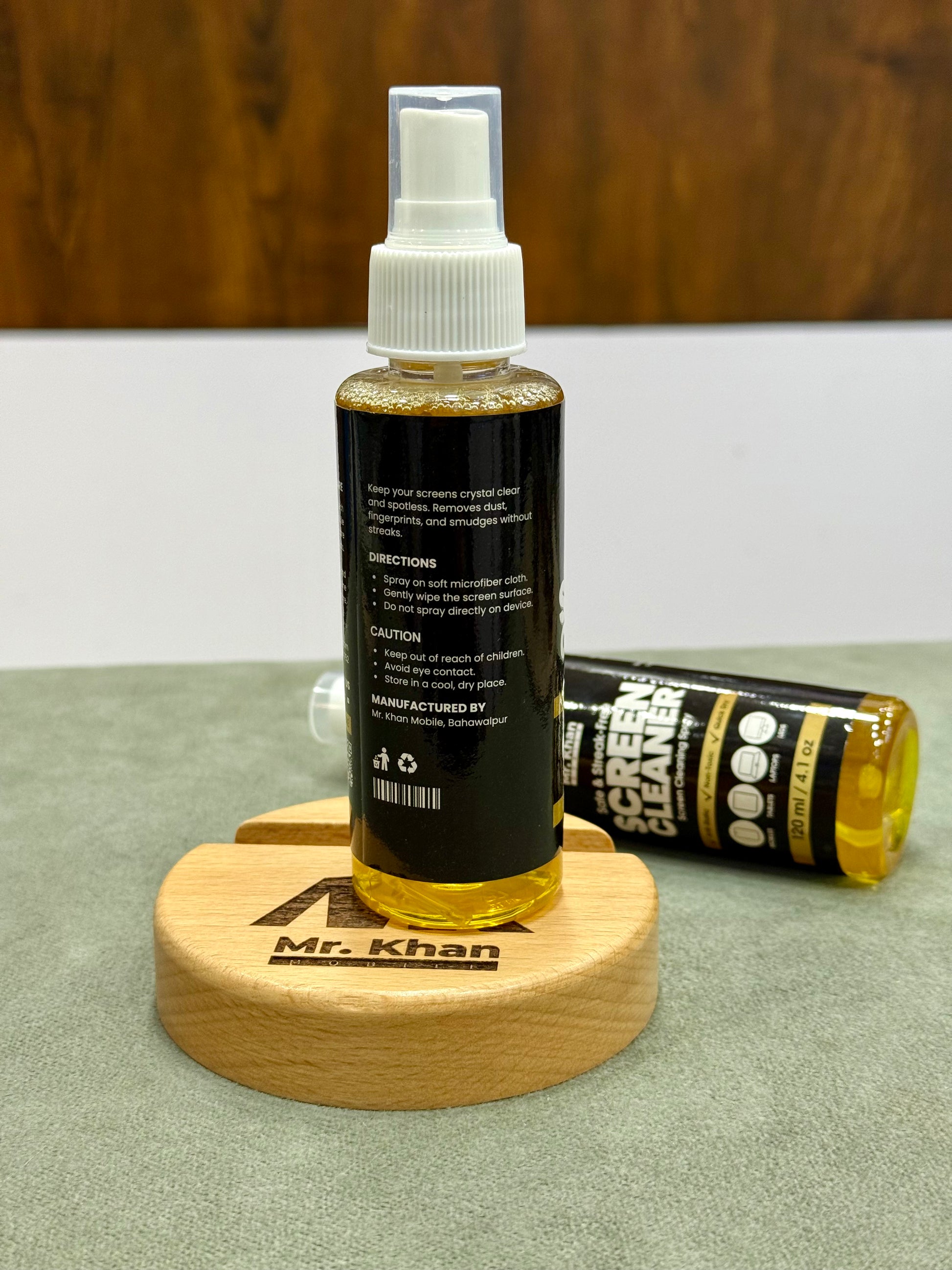 Bottle of screen cleaner with a wooden coaster and tube on a surface